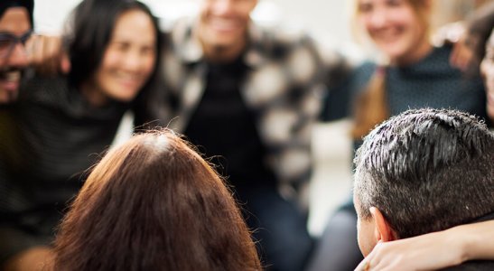 grupo de pessoas sorrindo abraçadas em círculo