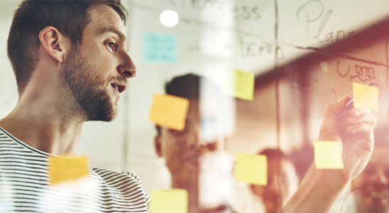 homem fazendo anotações em quadro de vidro