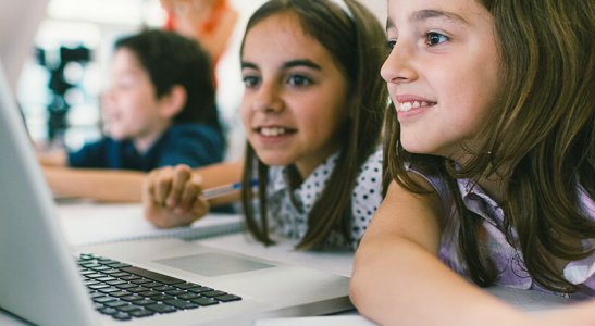 crianças sentadas juntas utilizando um notebook