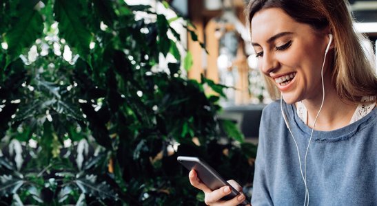 moça loira de perfil sorrindo para a tela do celular