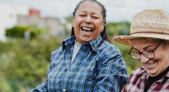 duas mulheres sorrindo em uma plantação ,representando a transformação social gerada pelo cooperativismo