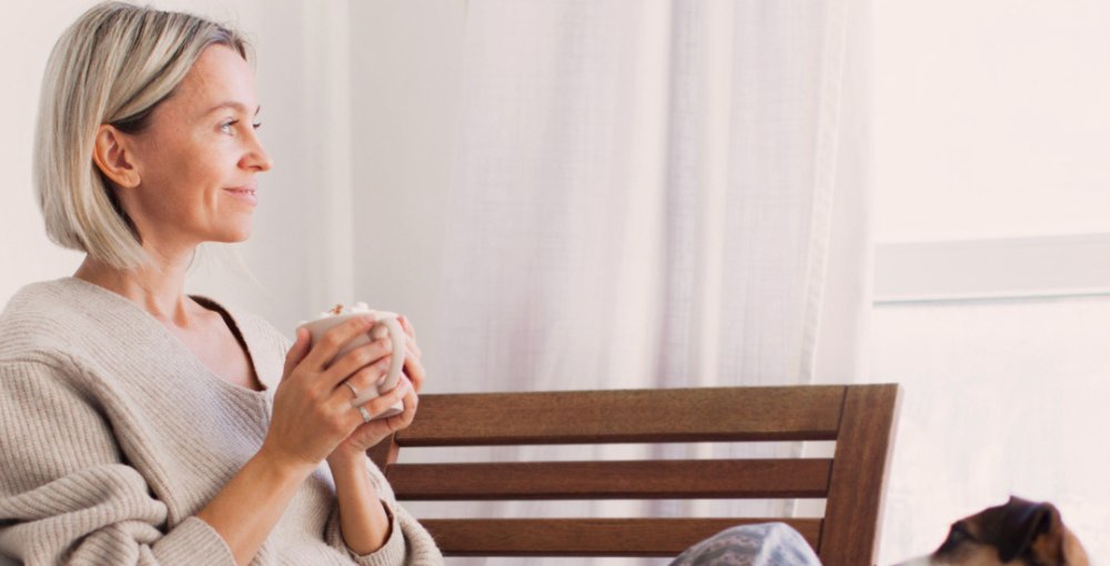Mulher apreciando uma bebida quente em casa durante o inverno 2025, em um ambiente aconchegante e iluminado.